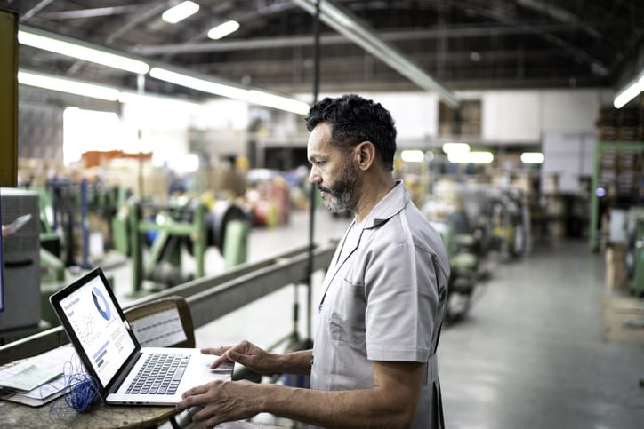 technician working on laptop in warehouse