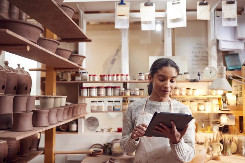 female potter in ceramics studio looking at tablet