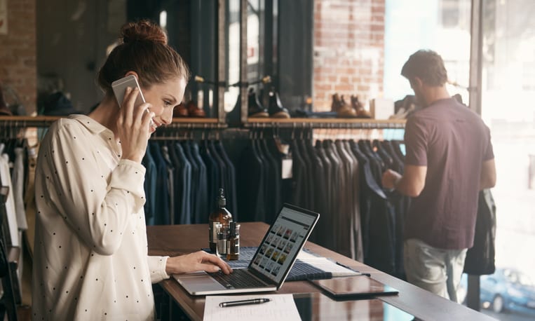 woman talking on the phone whilst looking at her laptop