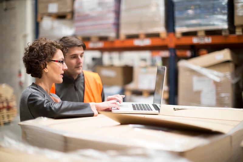 warehouse workers looking at laptop