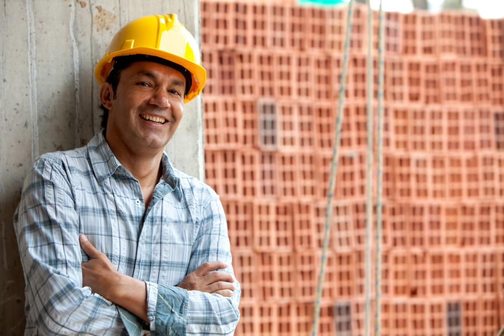 Happy male construction worker wearing a helmet and smiling Happy male construction worker wearing a helmet and smiling